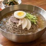차가운 육수와 면 위에 오이, 배, 고기와 삶은 달걀을 올린 물냉면