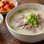 뽀얀 국물에 소고기와 파를 담고 밥과 깍두기를 곁들인 설렁탕